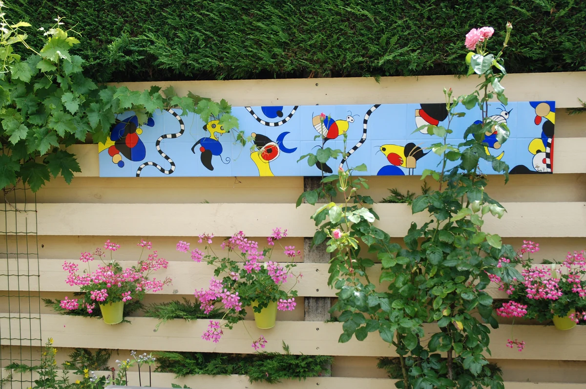 Lang blauw beschilderd paneel tussen planten in een tuin